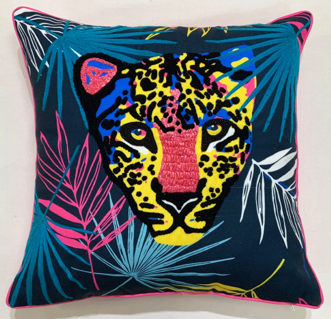 Bright leopard face among palm fronds on a throw pillow with hot pink piping